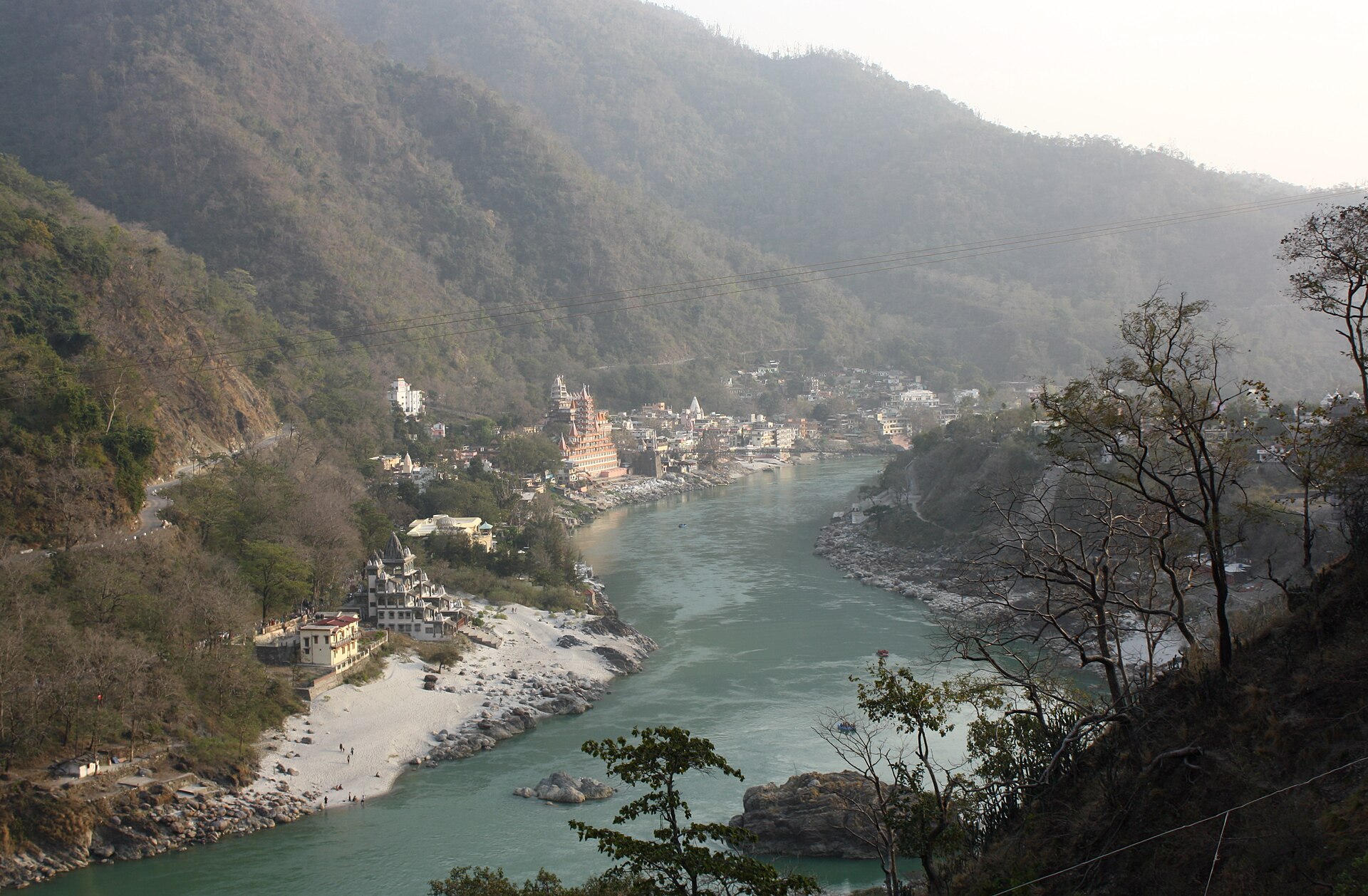 The Lakshman Jhula suspension bridge across the Ganga at Rishikesh, with temples and forested hills behind