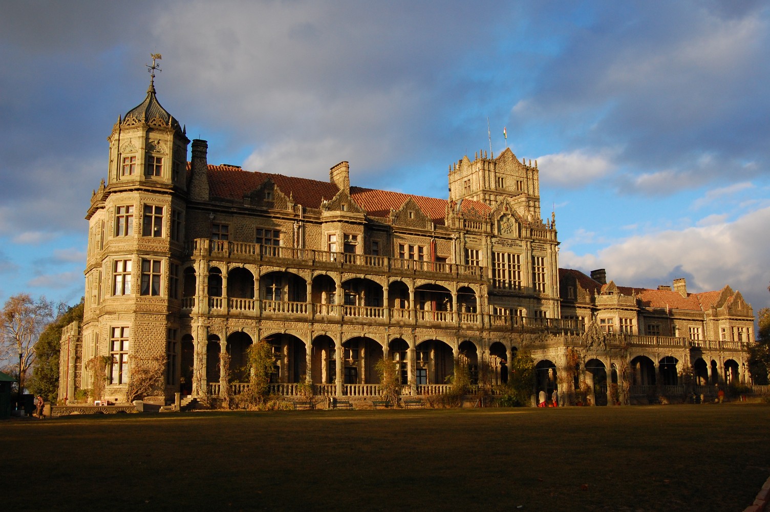 The Viceregal Lodge in Shimla, a grey stone Jacobethan mansion with turrets and arcaded verandas, lit by low afternoon sun